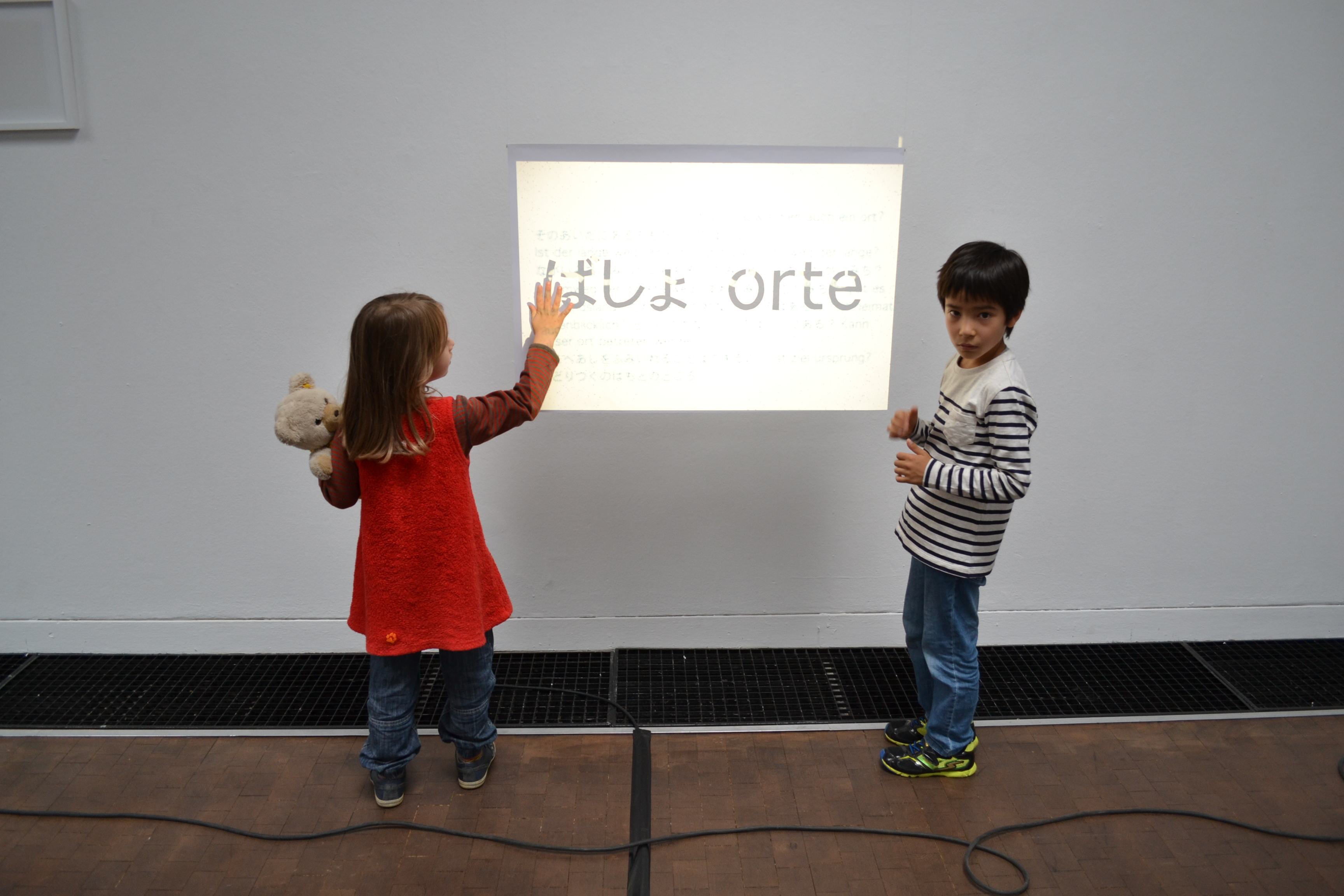 Zwei Kinder stehen vor einem projizierten Bild mit Schrift