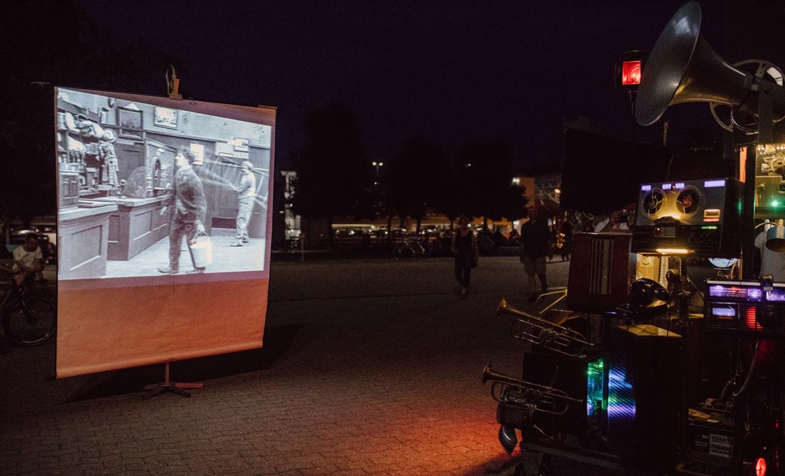 Schwarzweiß Film wird draußen auf einer weißen Fläche gezeigt. Rechts stehen allerlei Retro-Medien