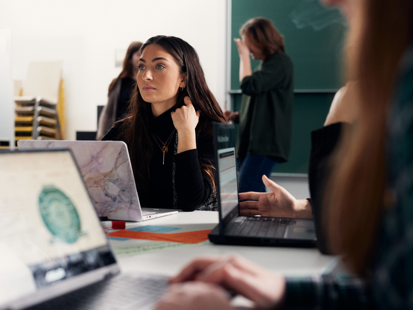 A young woman looks intently, a laptop is in front of her.