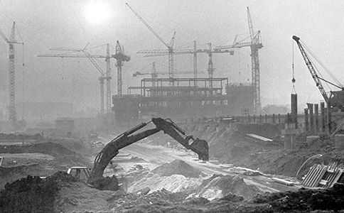 Die Baustelle des Universittshauptgebudes im Jahr 1972. Im Vordergrund grbt ein Bagger in der Erde. Im Hintergrund ist der beginnende Rohbau des Hauptgebudes mit zahlreichen Krnen zu sehen.