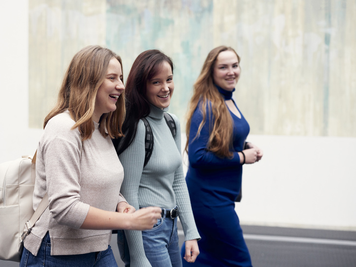 Drei junge Frauen laufen gemeinsam durch die Uni-Halle.